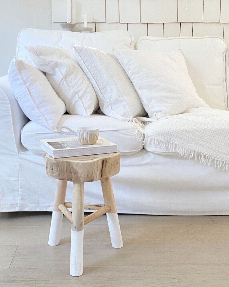 white sofa with two tone wooden stool and handcrafted coffee mug